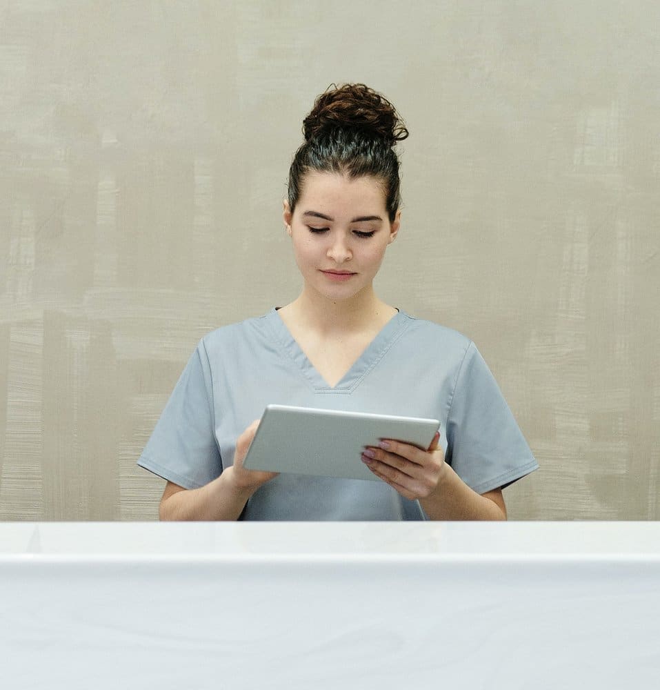 medical assistant standing in front of desk with a tablet